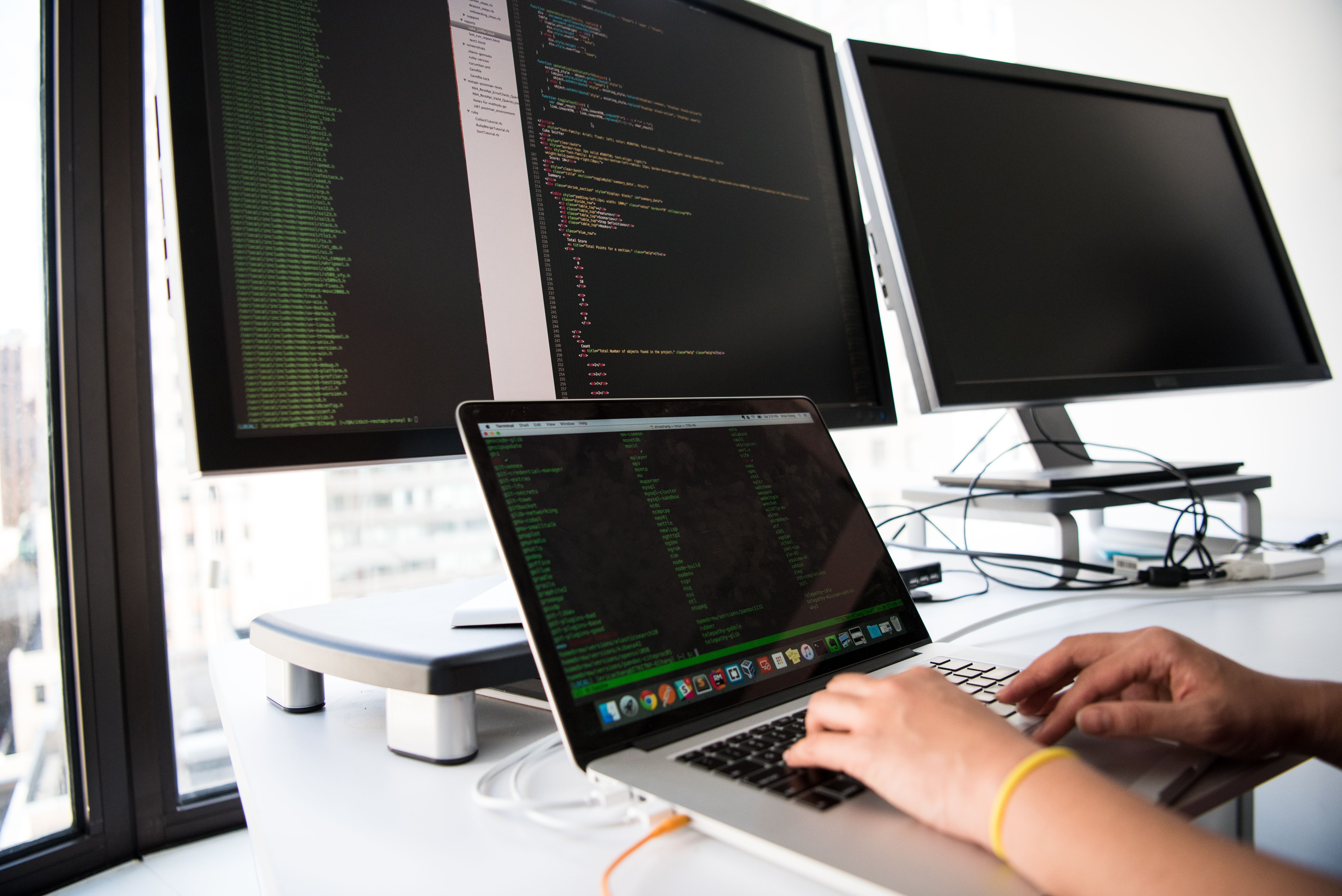 Developer at a workstation with multiple monitors in a modern office